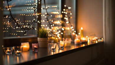 Picture of a window ledge with fairy lights, candles and a small plant