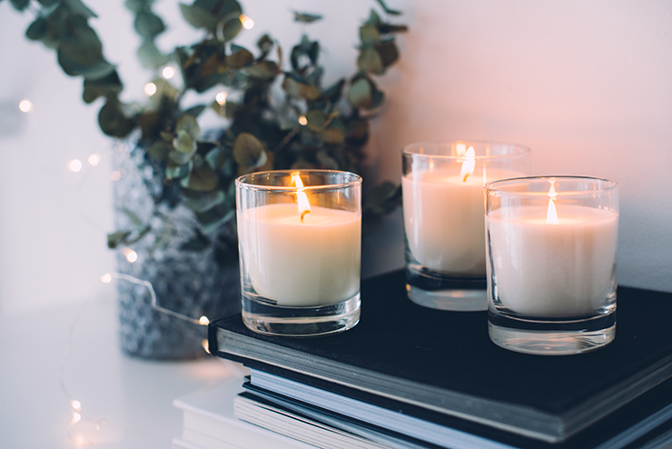 Picture of three lit candles next to a plant