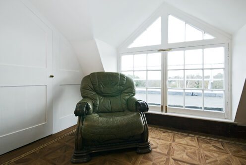 Picture of a loft room with green armchair and window
