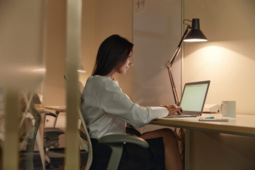 Picture of a woman at her desk with lamp and computer