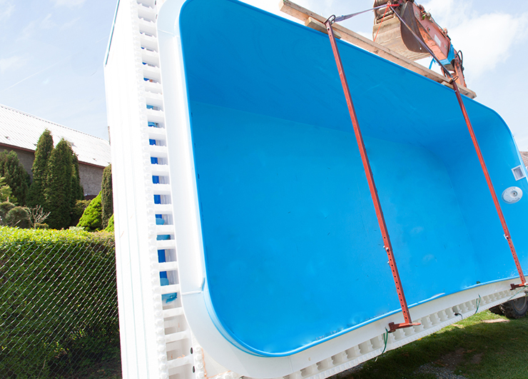 Picture of a swimming pool shell being transported by a crane