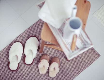 Picture of two sets of slippers adult and child on a mat beside a chair