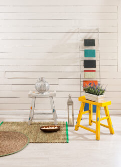 Picrture of a wooden wall with orange low stool with a flower pot and other decorations