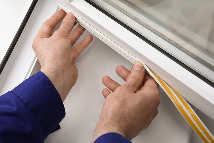 Picture of hands sticking a draught strip to window 