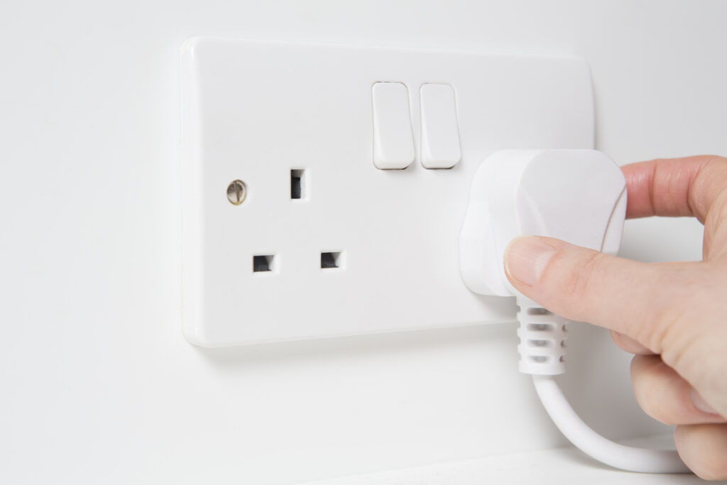 Picture of a hand plugging in a plug into socket