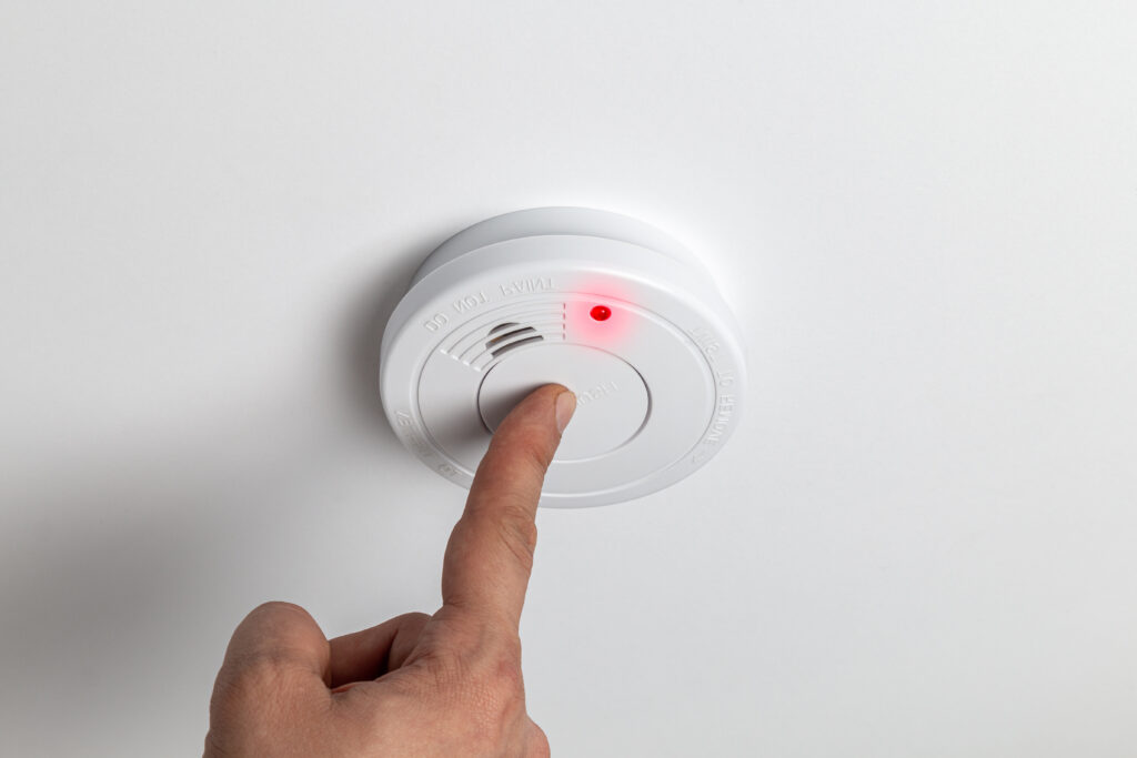 Picture of a finger pressing button on a smoke alarm