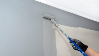 Picture of a painter rolling grey paint onto wall
