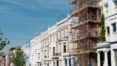 Picture of a row of white houses with blue sky and scaffolding on one home