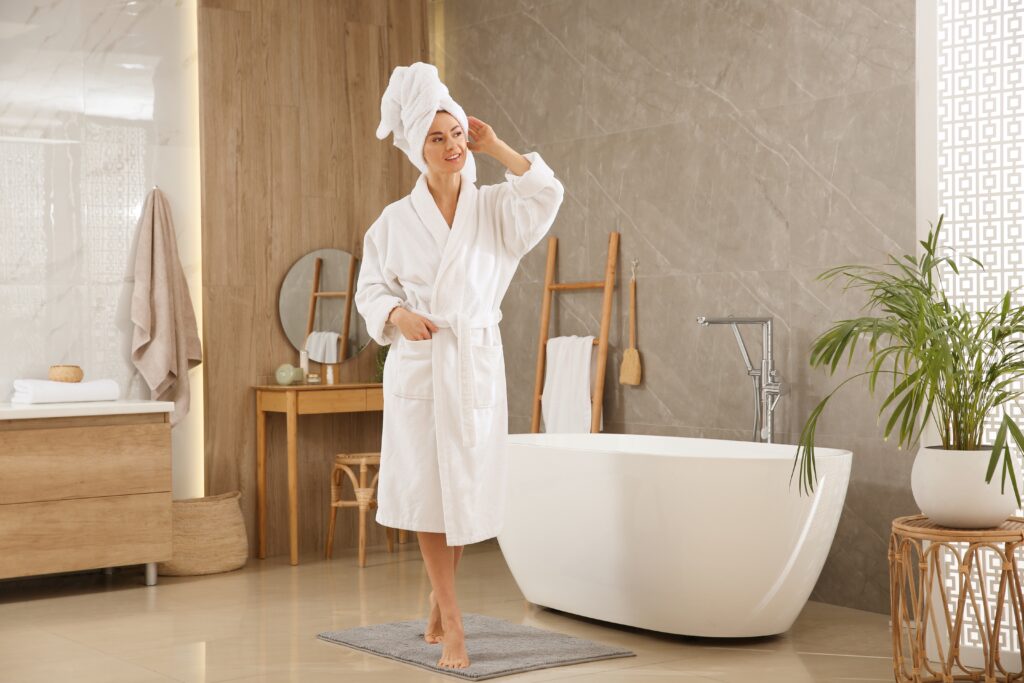 Picture of a person in robe in a bathroom with plants and freestanding tub