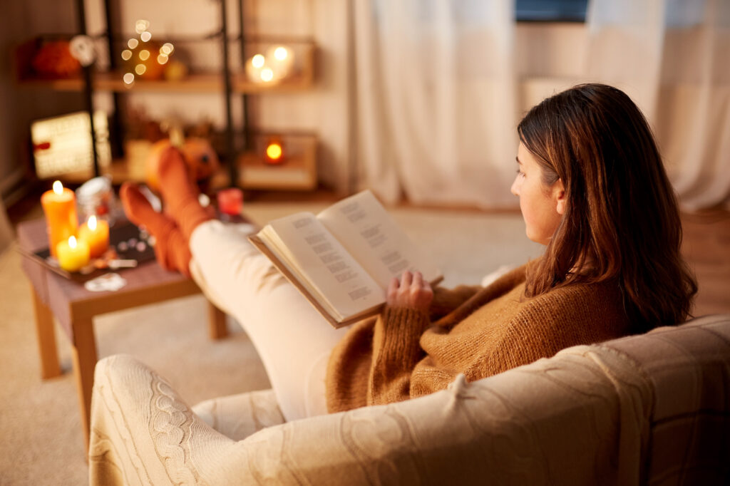 Picture of a woman on sofa reading with candles and cosy autumn decor living room