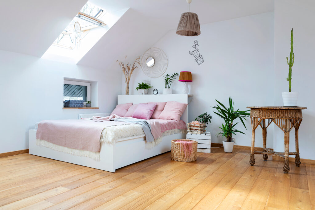 Picture of an attic bedroom with pink sheets and wooden floors