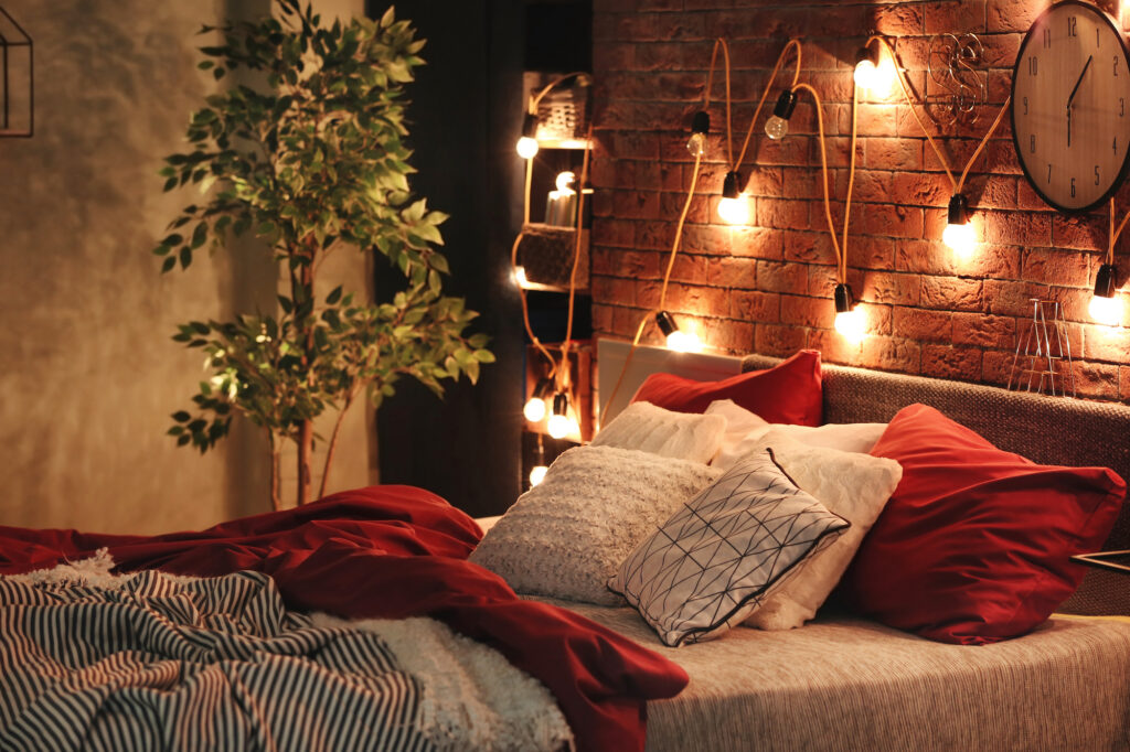 Picture of a bed with cosy lights hanging behind the bed frame