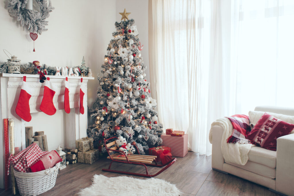 Picture of a living room with christmas tree and christmas decorations including red stockings over fireplace