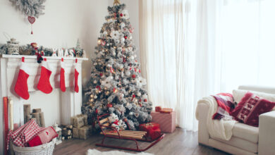 Picture of a living room with christmas tree and christmas decorations including red stockings over fireplace