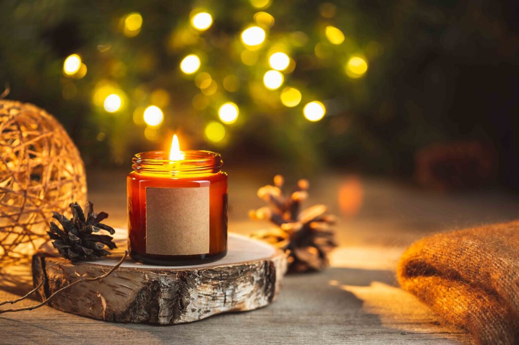 Picture of a candle on a cut piece of log with a christmas tree in the background