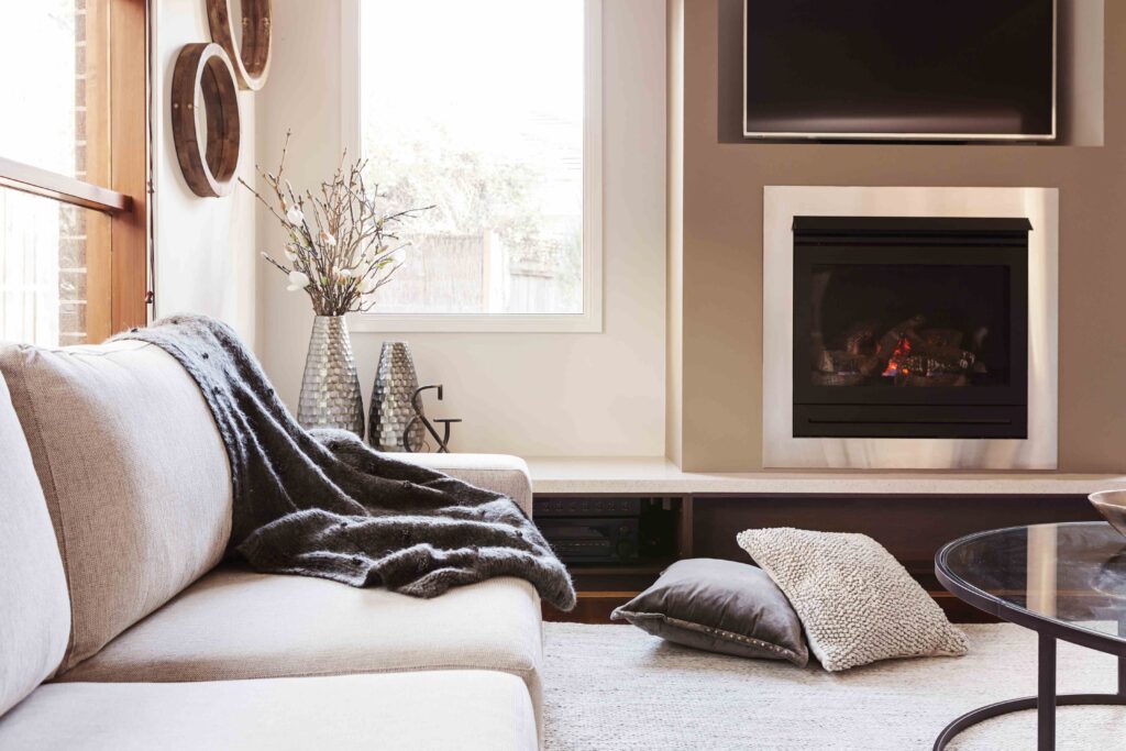 Picture of a living room with fireplace and a white sofa with grey throw over it